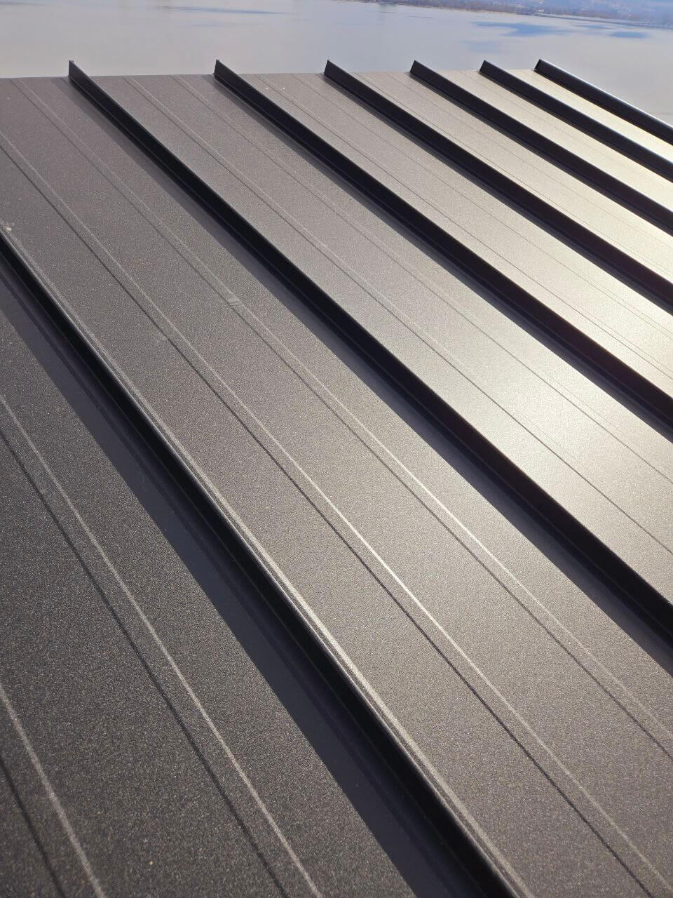 On-Site Panel Fabrication – Standing Seam Roofing in Kamloops Westpeak Metal Roofing crew member working on-site using standing seam panel equipment in Kamloops.