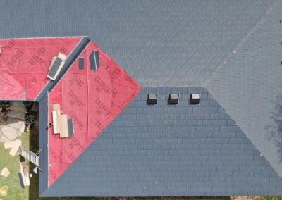 Roofer aligning metal slate panels on a pitched residential roof in the Okanagan.