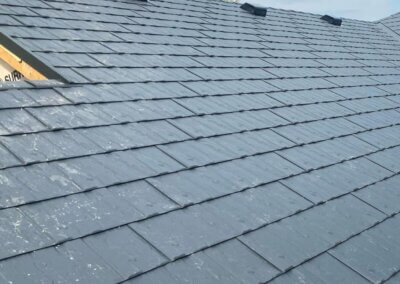Crew member securing a metal slate roofing panel during a residential installation.